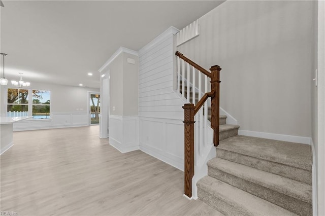 stairway with wood-type flooring and a chandelier