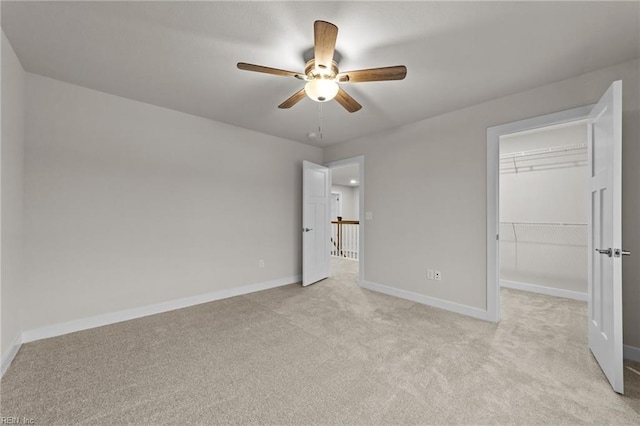 unfurnished bedroom with a spacious closet, light carpet, ceiling fan, and a closet