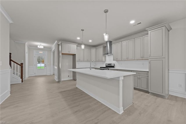 kitchen featuring hanging light fixtures, gray cabinetry, stainless steel range, and wall chimney exhaust hood