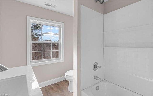 bathroom featuring wood-type flooring, toilet, and tiled shower / bath