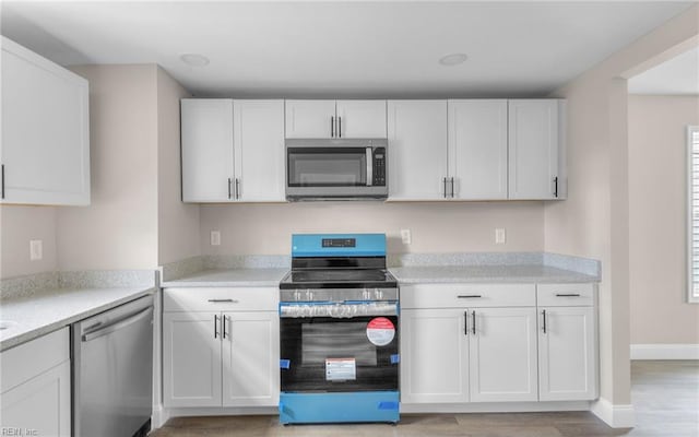 kitchen with white cabinetry, stainless steel appliances, and light hardwood / wood-style flooring