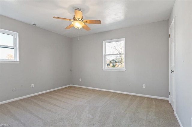 carpeted spare room featuring ceiling fan and a healthy amount of sunlight