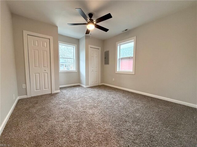 unfurnished bedroom with multiple closets, multiple windows, electric panel, and carpet