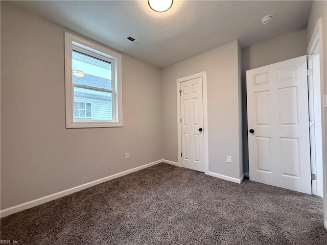 unfurnished bedroom with dark colored carpet and a closet