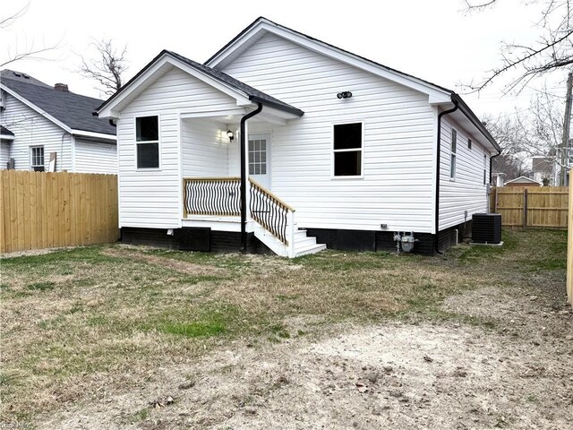 rear view of property featuring a yard and central AC unit