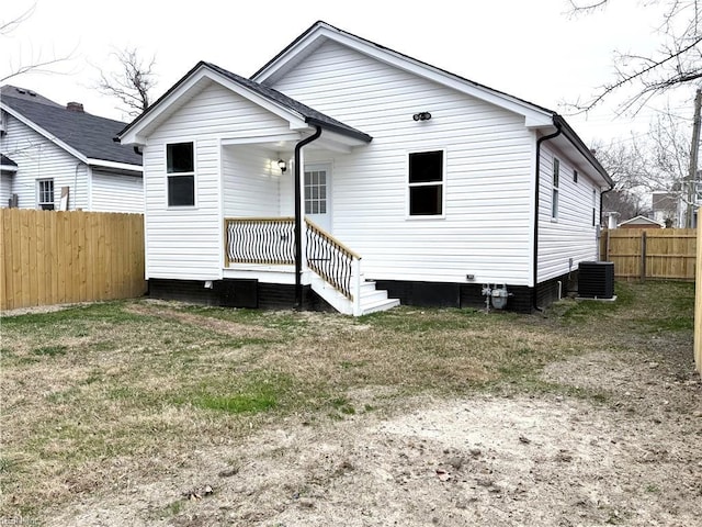 rear view of property featuring a yard and central AC unit