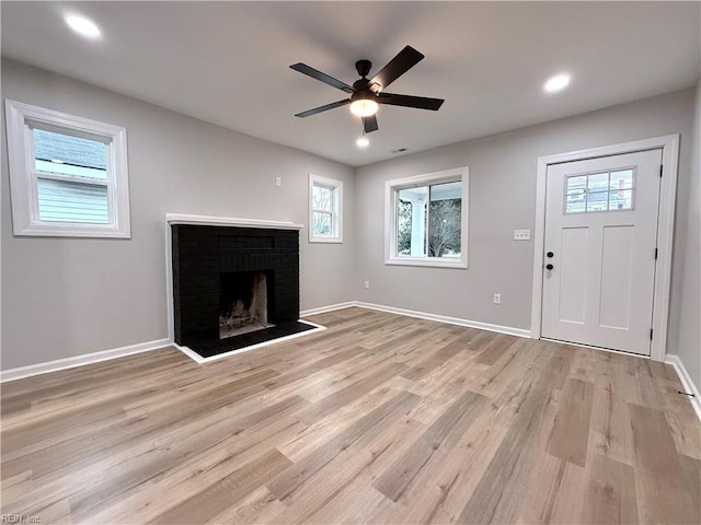 unfurnished living room featuring ceiling fan, a fireplace, and light hardwood / wood-style floors