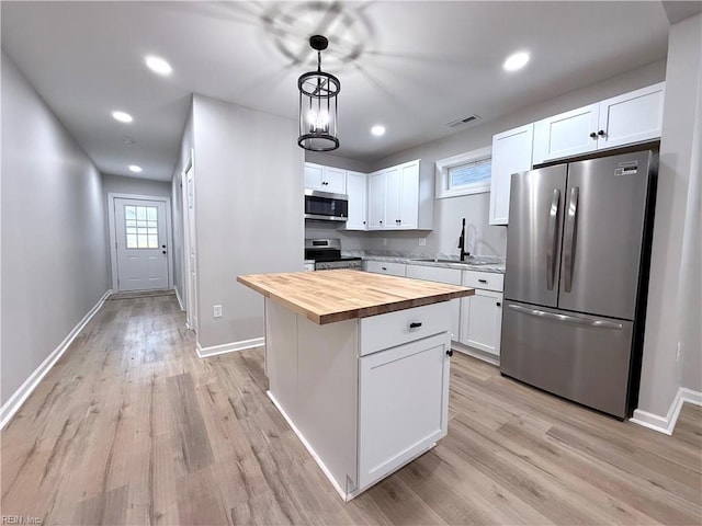 kitchen with pendant lighting, wooden counters, stainless steel appliances, a center island, and white cabinets