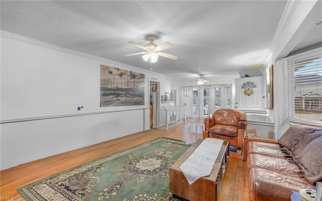 living room with wood-type flooring, ornamental molding, and ceiling fan