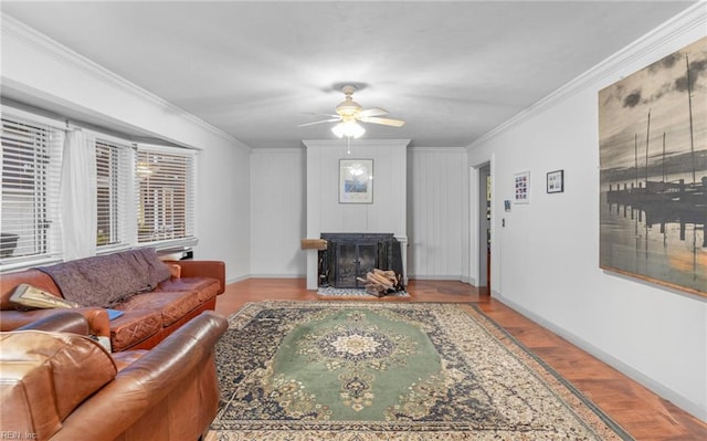 living room featuring ornamental molding, light wood-type flooring, ceiling fan, and a fireplace