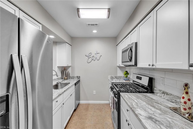 kitchen with sink, light stone countertops, white cabinets, and appliances with stainless steel finishes