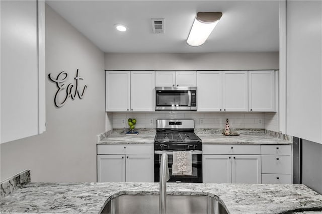 kitchen with backsplash, appliances with stainless steel finishes, and white cabinets