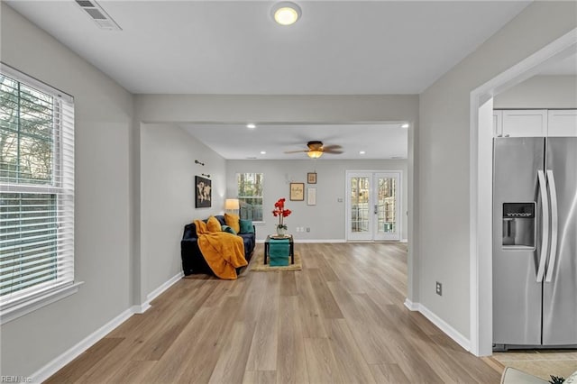 living area with ceiling fan, light hardwood / wood-style floors, and french doors