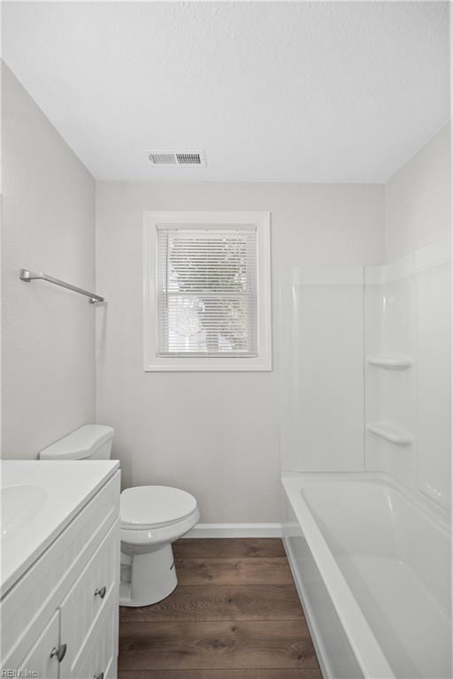 full bathroom featuring hardwood / wood-style flooring, vanity,  shower combination, and toilet