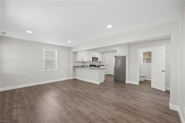 unfurnished living room with sink, plenty of natural light, and dark hardwood / wood-style floors