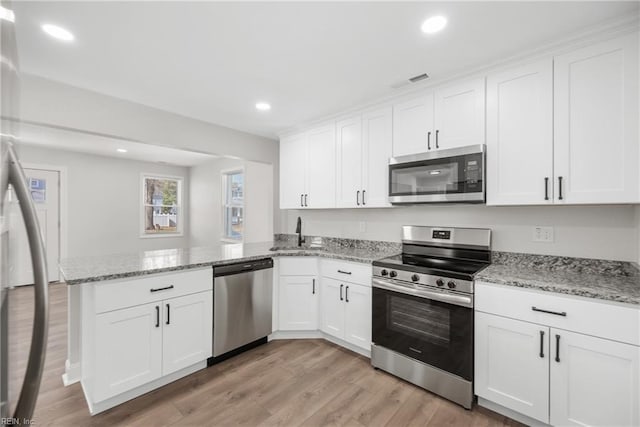 kitchen with sink, kitchen peninsula, white cabinets, and appliances with stainless steel finishes