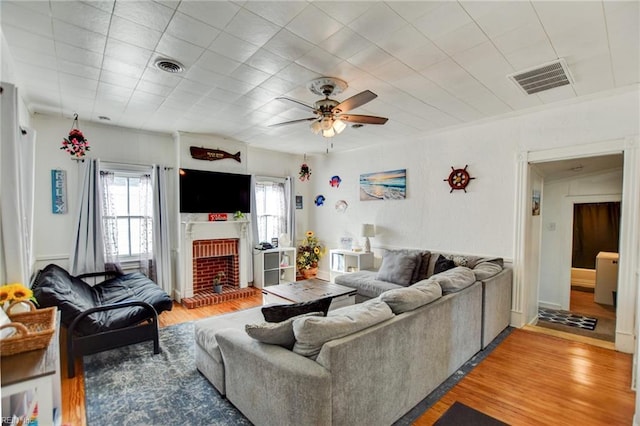 living room with ceiling fan, wood-type flooring, and a fireplace