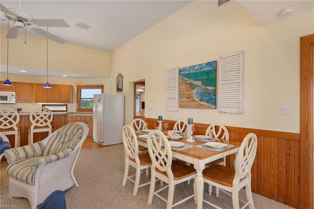 dining space with ceiling fan and wood walls