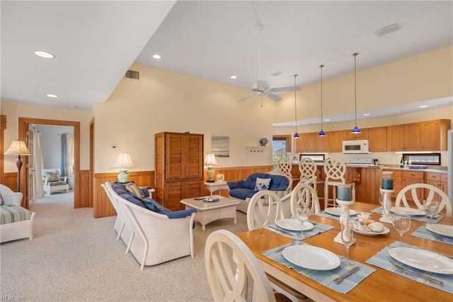 carpeted dining space with ceiling fan and a high ceiling