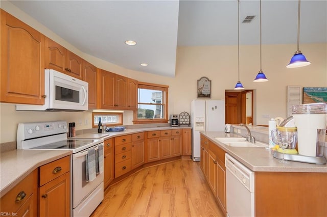 kitchen featuring hanging light fixtures, white appliances, sink, and light wood-type flooring