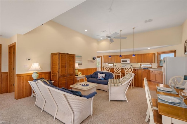 living room featuring ceiling fan, a high ceiling, light carpet, and a wealth of natural light