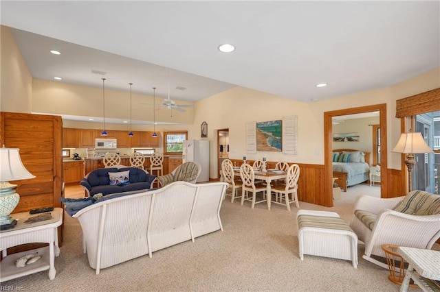 living room featuring wooden walls, light colored carpet, and ceiling fan