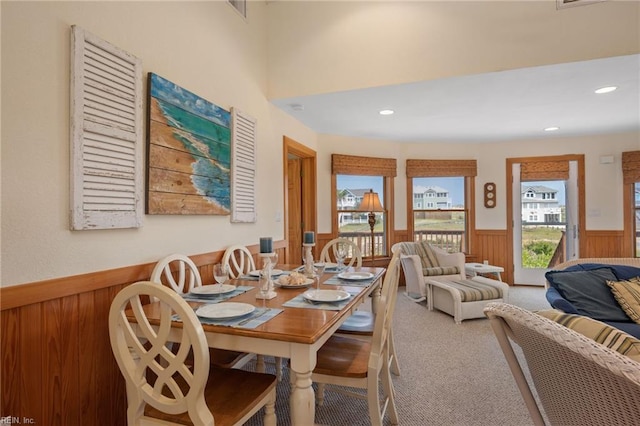 carpeted dining area featuring wood walls