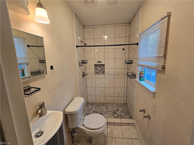 bathroom featuring plenty of natural light, tiled shower, sink, and toilet