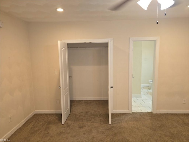 unfurnished bedroom featuring dark carpet, a closet, ceiling fan, and a spacious closet