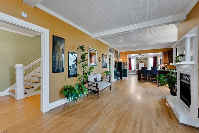 interior space with beam ceiling, ornamental molding, and light hardwood / wood-style floors