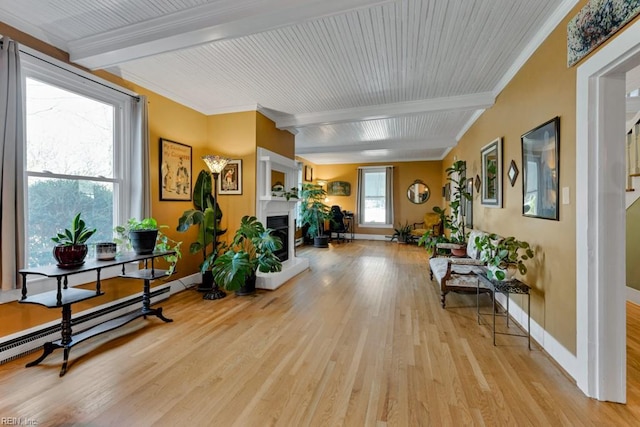 interior space featuring beamed ceiling, ornamental molding, light wood-type flooring, and baseboard heating