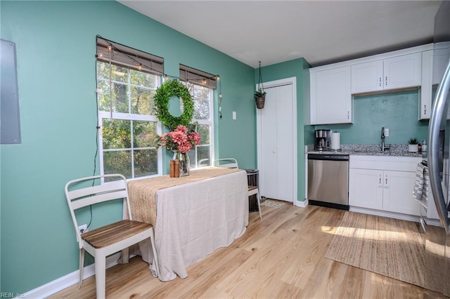 kitchen with sink, white cabinetry, light wood-type flooring, stainless steel dishwasher, and electric panel