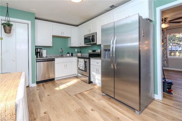 kitchen featuring white cabinetry, stainless steel appliances, light stone countertops, and light hardwood / wood-style floors