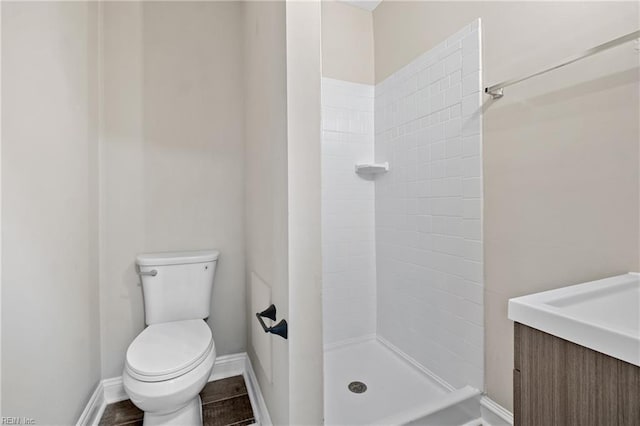 bathroom with vanity, a tile shower, and toilet