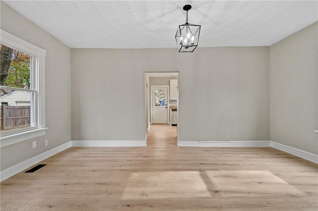 unfurnished dining area featuring a chandelier and light wood-type flooring