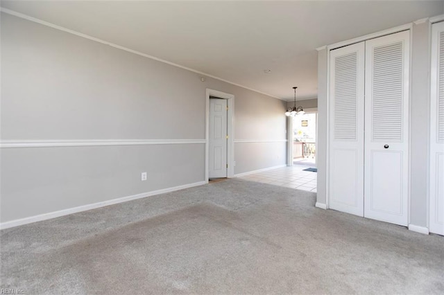 spare room featuring light carpet, ornamental molding, and a chandelier