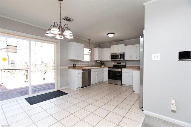 kitchen featuring sink, hanging light fixtures, ornamental molding, appliances with stainless steel finishes, and white cabinets