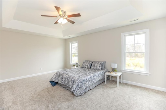 bedroom featuring ceiling fan, a raised ceiling, and carpet floors