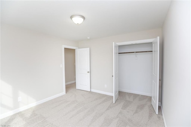 unfurnished bedroom featuring light carpet and a closet