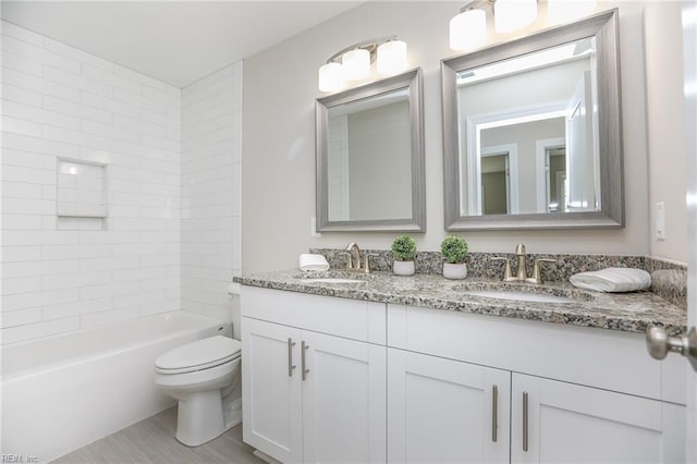 full bathroom featuring vanity, tiled shower / bath, and toilet