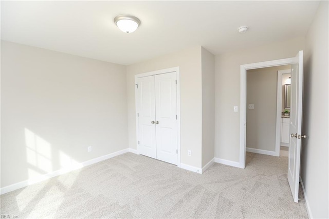 unfurnished bedroom with light colored carpet and a closet