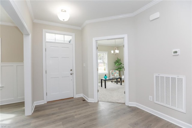 entrance foyer with ornamental molding, light hardwood / wood-style flooring, and a notable chandelier