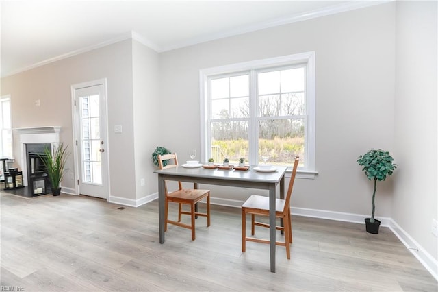 dining area with ornamental molding and light hardwood / wood-style flooring