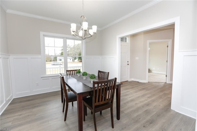 dining room with ornamental molding, an inviting chandelier, and light wood-type flooring