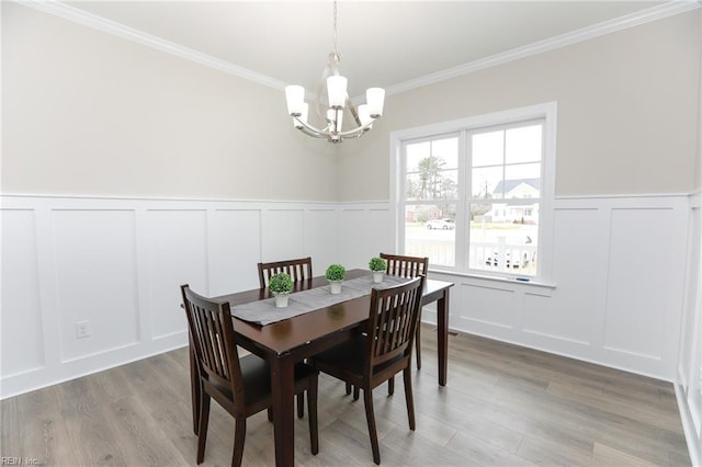 dining space with an inviting chandelier, ornamental molding, and light hardwood / wood-style flooring