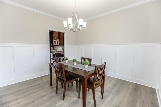 dining space featuring an inviting chandelier, ornamental molding, and light hardwood / wood-style floors