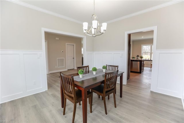 dining room featuring a notable chandelier, crown molding, and light hardwood / wood-style floors