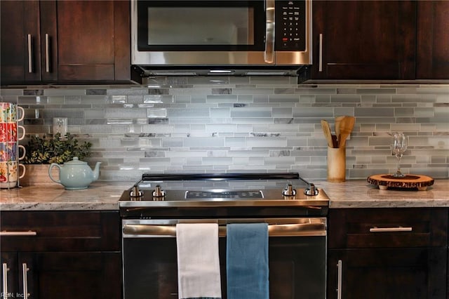 kitchen with dark brown cabinetry, backsplash, stainless steel appliances, and light stone countertops