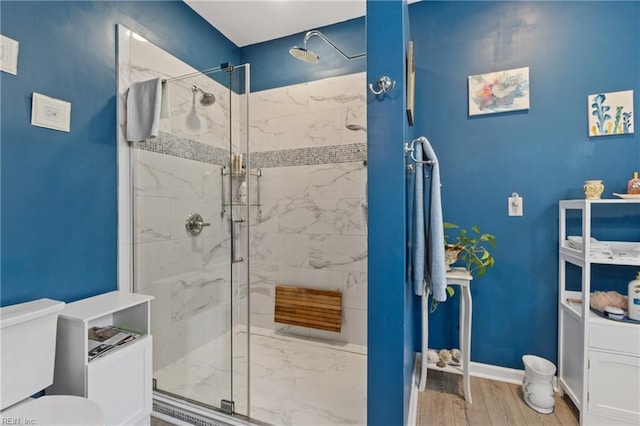 bathroom with hardwood / wood-style flooring, a shower with door, and toilet