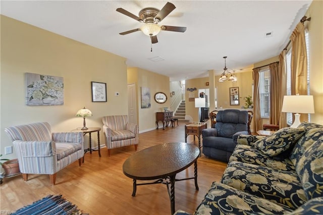 living room featuring hardwood / wood-style flooring and ceiling fan with notable chandelier